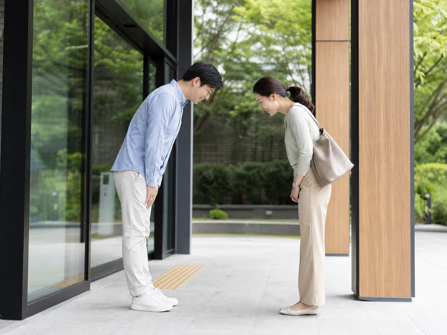 Two Korean adults exchanging a polite greeting with a small bow in a contemporary setting